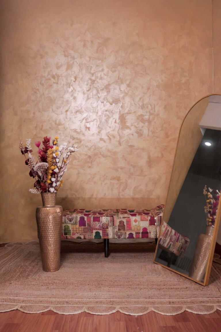 Lifestyle studio setup at Lens Grove Studio, a professional photo and video shoot rental space in Delhi, featuring a textured beige wall backdrop, decorative floor vase with dried flowers, patterned bench seating, and a standing mirror, styled for fashion, lifestyle, and editorial photography.