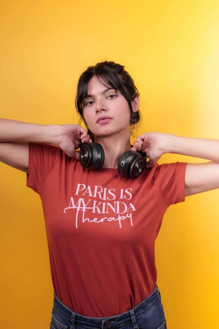 Casual fashion portrait shot at Lens Grove Studio, a professional photo and video shoot rental space in Delhi, featuring a female model wearing a graphic t-shirt, denim jeans, and sneakers, posing against a bold yellow backdrop with clean studio lighting for lifestyle and editorial photography.