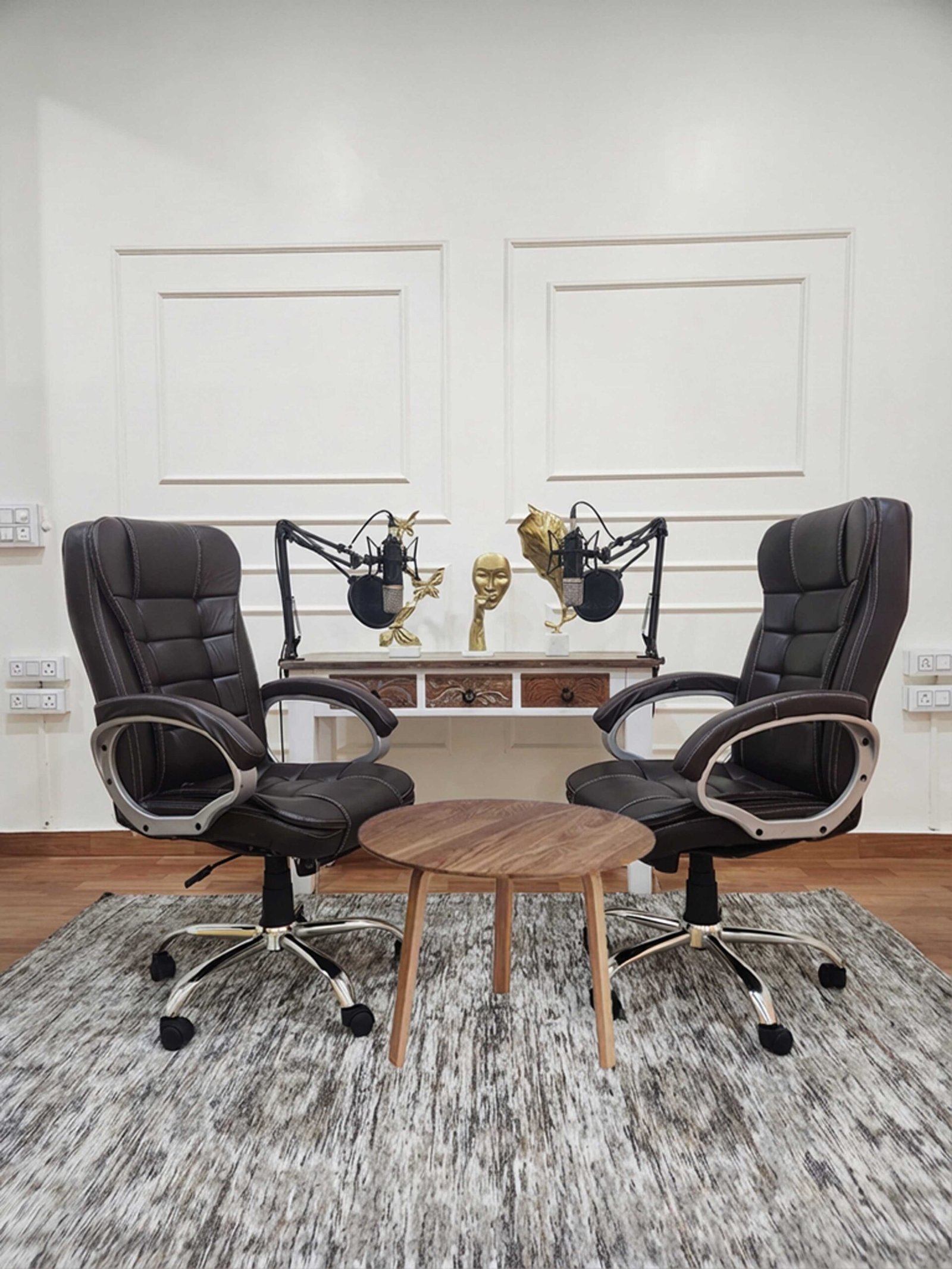 Podcast recording setup at Lens Grove Studio, a professional photo and video shoot rental space in Delhi, featuring two comfortable chairs, microphones on adjustable boom arms, a central table, and acoustic-friendly décor, designed for high-quality podcast and interview recordings.