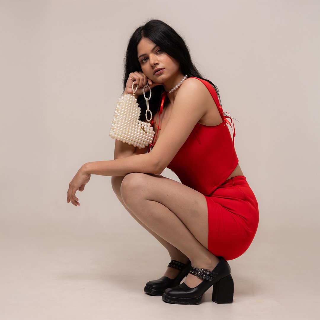 Fashion portrait shot at Lens Grove Studio, a professional photo and video shoot rental space in Delhi, featuring a female model wearing a red outfit and black heels, posing against a clean neutral background with soft studio lighting for editorial and portfolio photography.